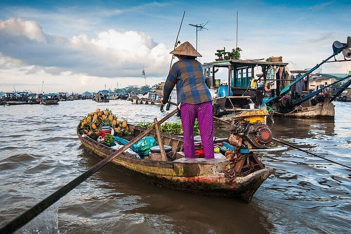Wooden boats loaded with fruit and vegetables at a floating market on the Mekong at sunrise