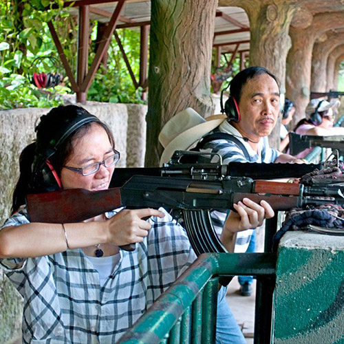 Two visitors firing rifles at the shooting range at the Cu Chi Tunnels