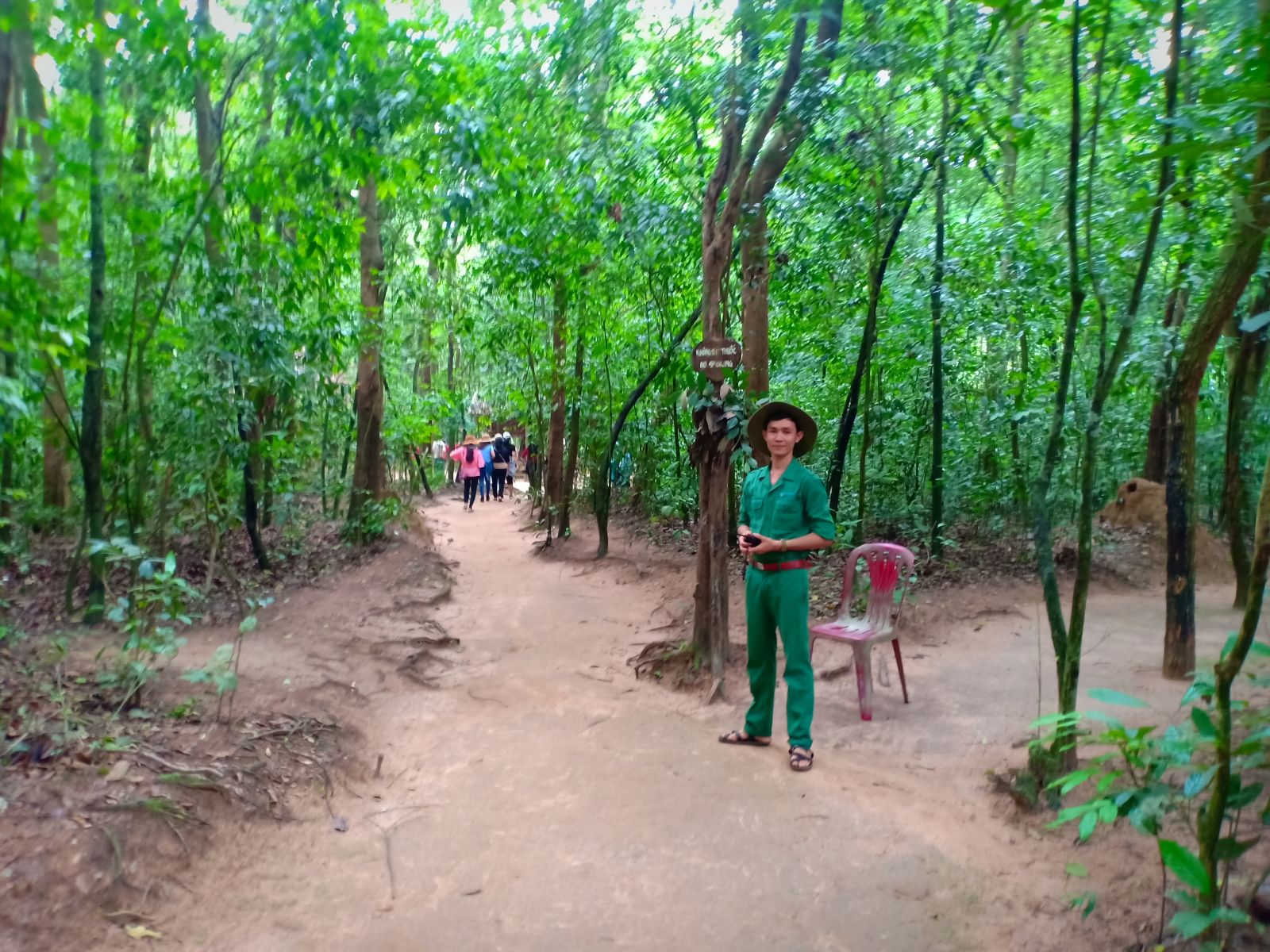 Visitors walking along a shaded dirt path at the Cu Chi Tunnels