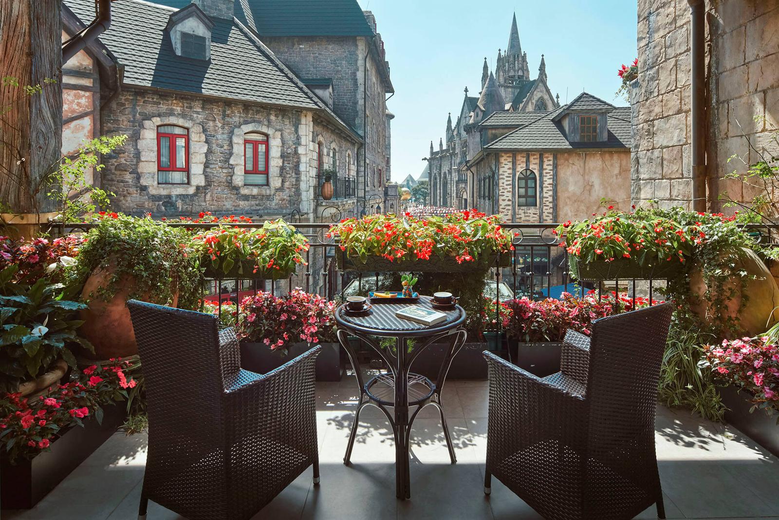 Café tables on a terrace in a European-style mountain village with people strolling