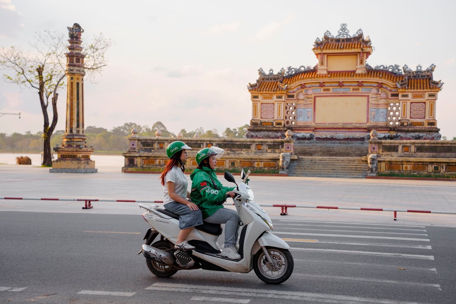 A Grab driver in a green jacket waiting on a city street in Vietnam