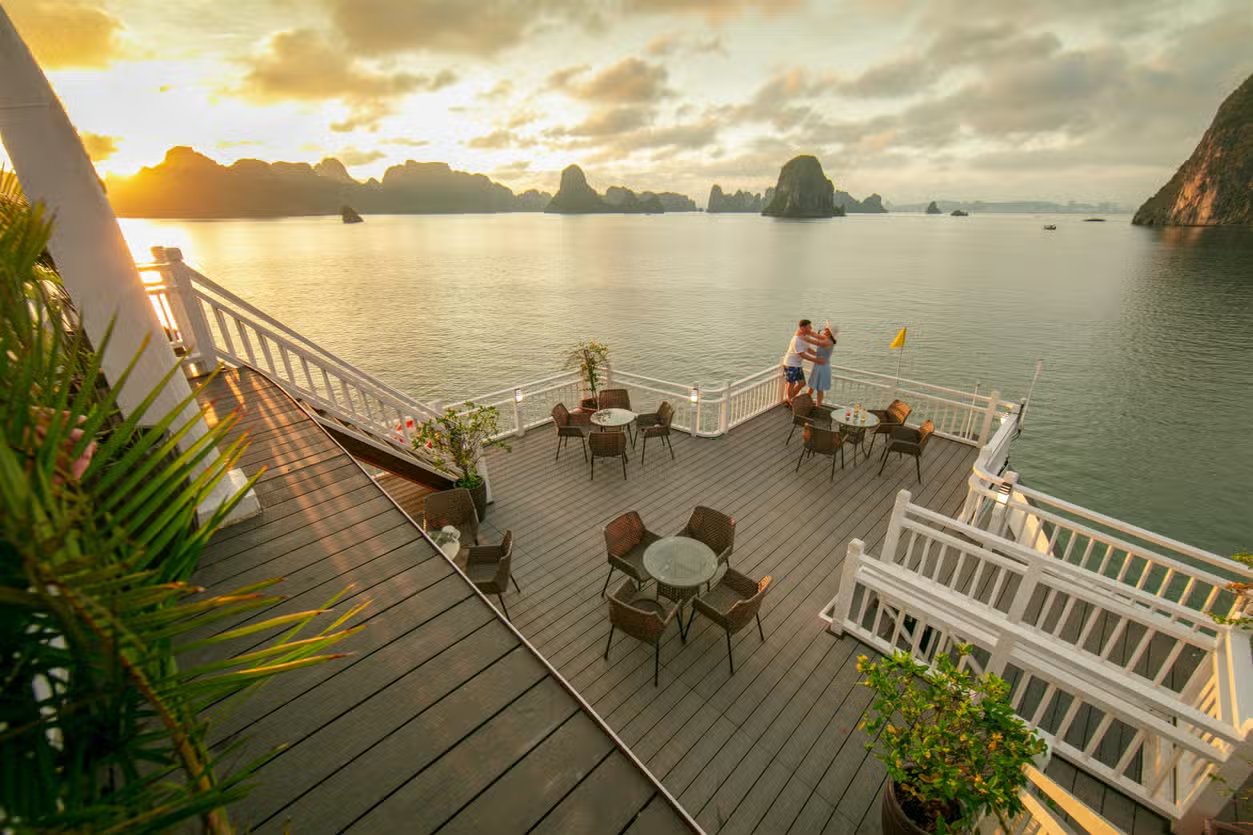 The sun deck of an overnight Ha Long Bay cruise at sunrise, with limestone islands on the horizon