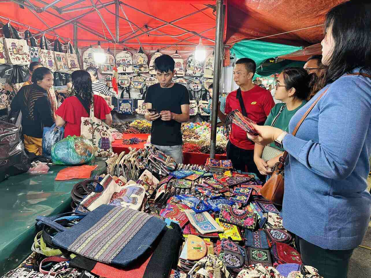 Indigo-dyed textiles and embroidered bags hanging at a market stall