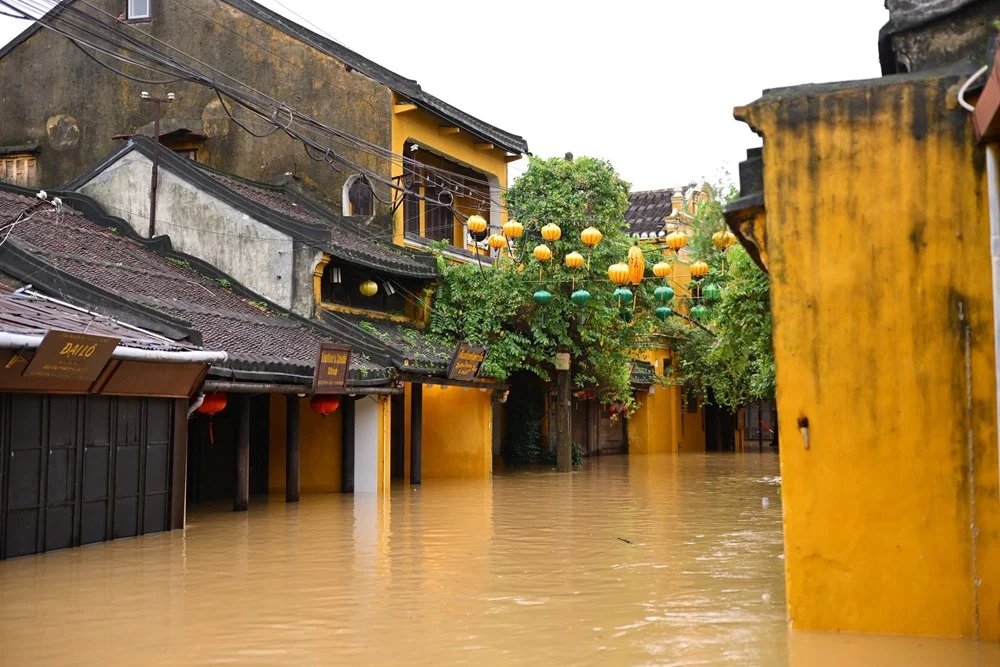Floodwater filling a street of yellow shophouses and lanterns in Hoi An old town during the rainy season