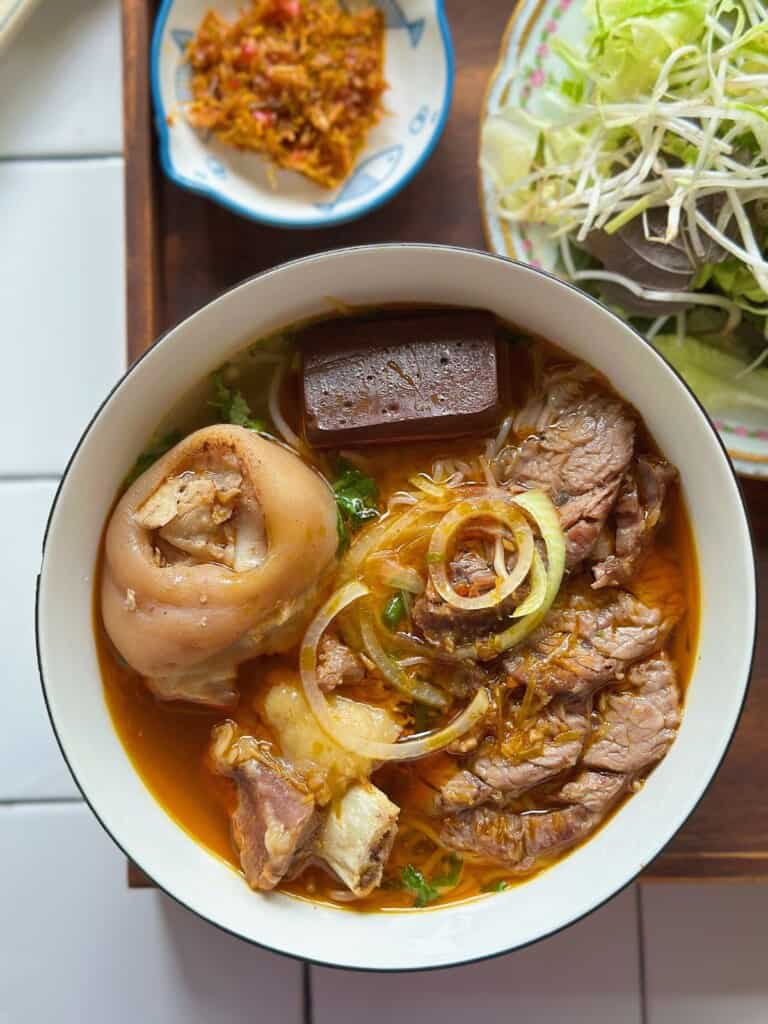 A bowl of bun bo Hue, spicy beef noodle soup with lemongrass, in Hue