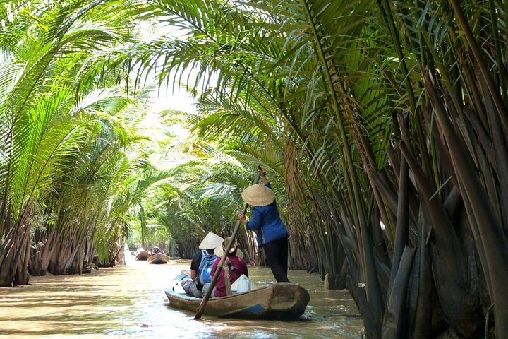 A sampan boat on a coconut-lined canal in the Mekong Delta