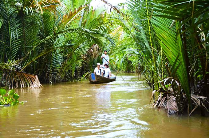 A small boat on a palm-lined canal in the Mekong Delta on a day trip from Ho Chi Minh City