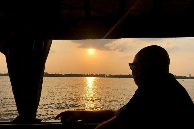 A boat silhouetted against an orange sunset on the Mekong River