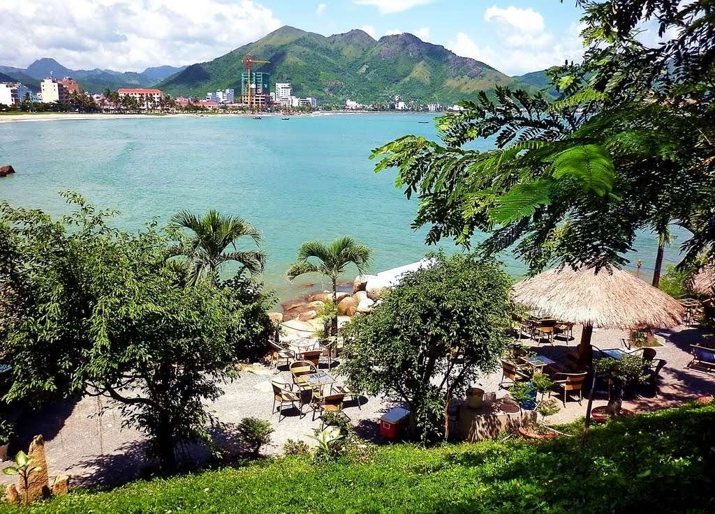 Vietnamese iced coffee on a table at a hillside cafe overlooking Hon Chong rock formations and the sea