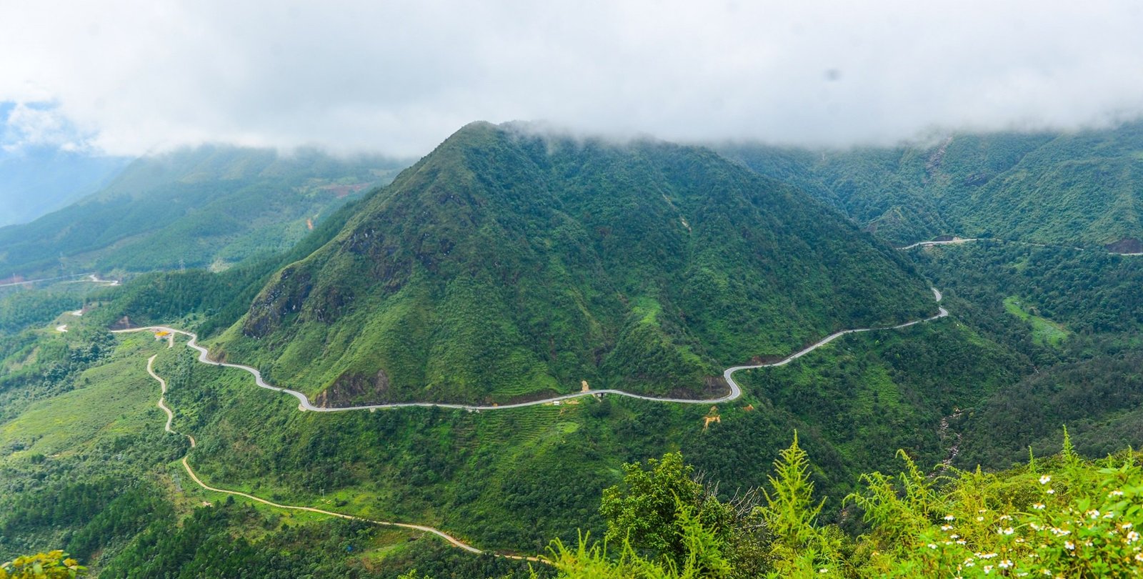 A winding mountain road at O Quy Ho pass with layers of mountains at sunset