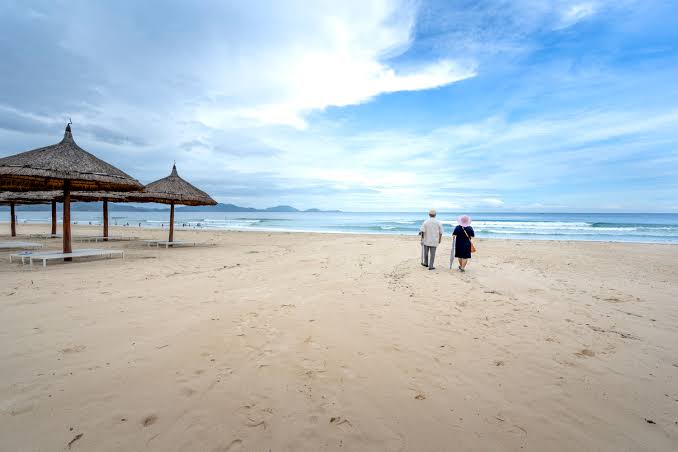 An older couple walking on a beach in Vietnam