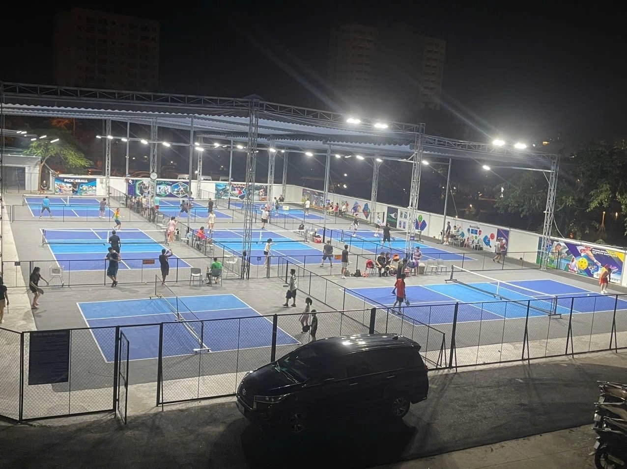 Rows of floodlit pickleball courts at night in Vietnam, busy with players