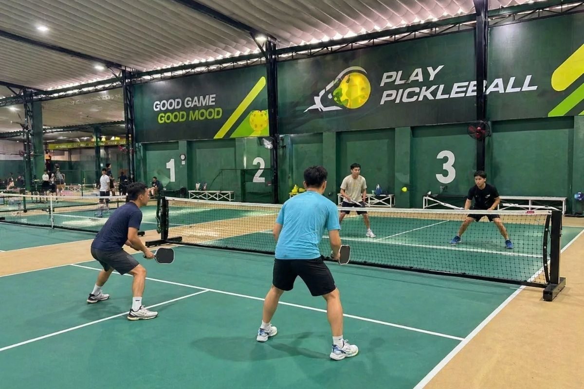 Indoor doubles pickleball game on numbered courts at a Da Nang club