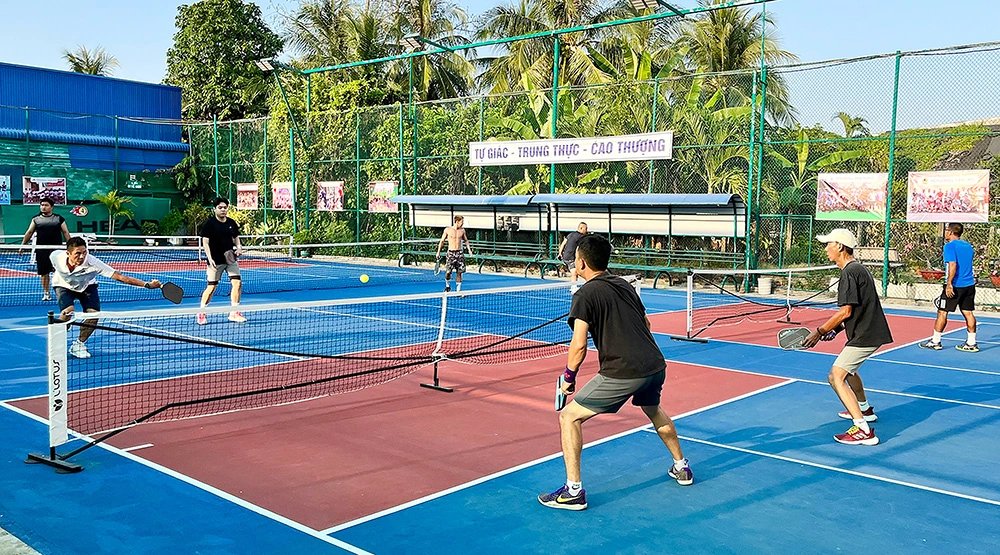 Four players in a doubles pickleball game on an outdoor court