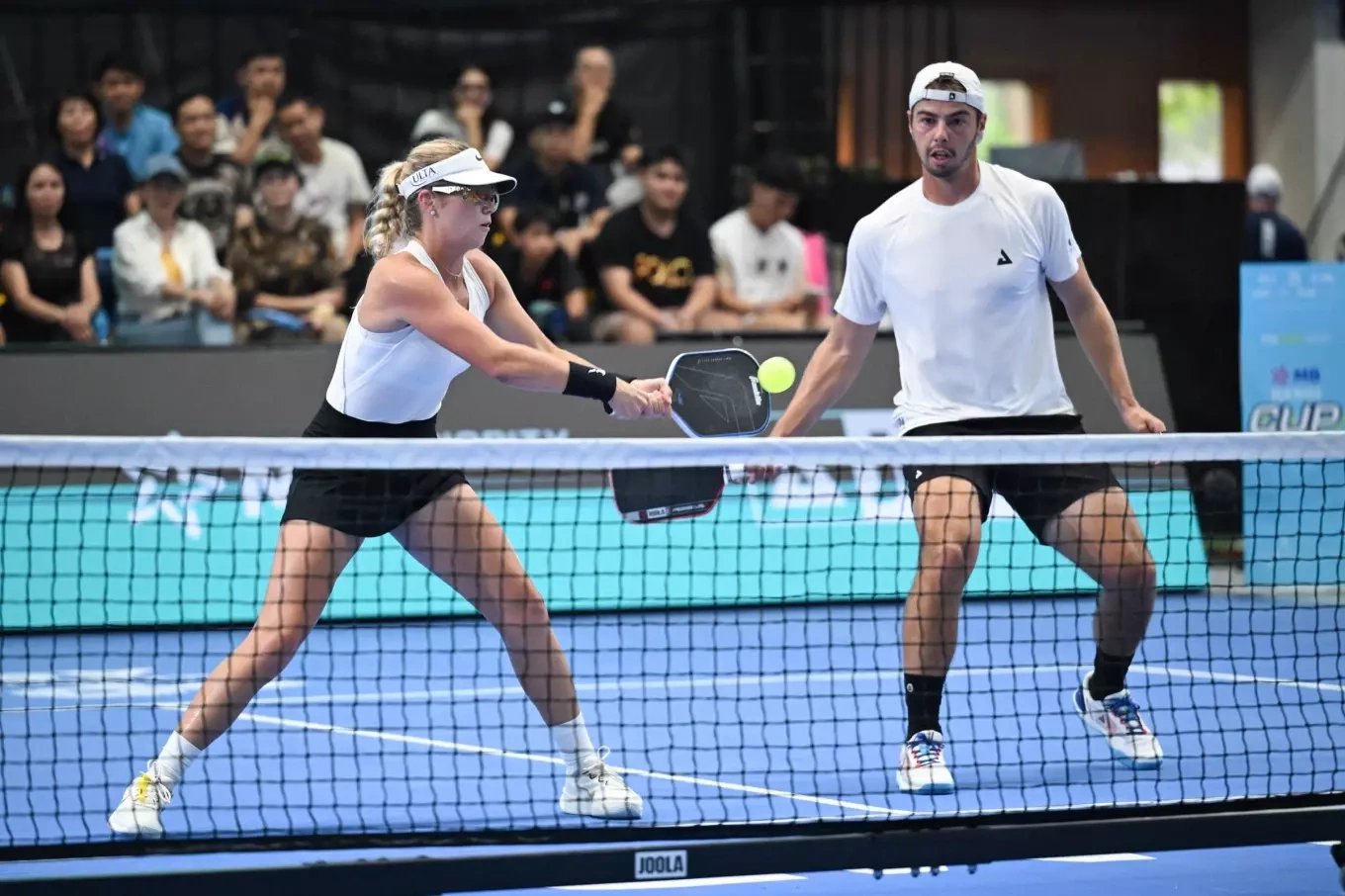 A mixed doubles pair at the net during a professional tournament match in Vietnam