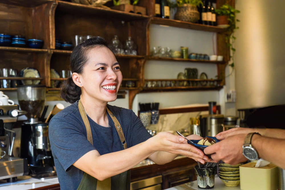 A café owner in Vietnam accepting money with both hands and a smile