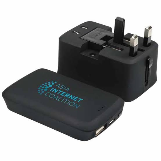 A universal travel adapter, a power bank and charging cables on a table