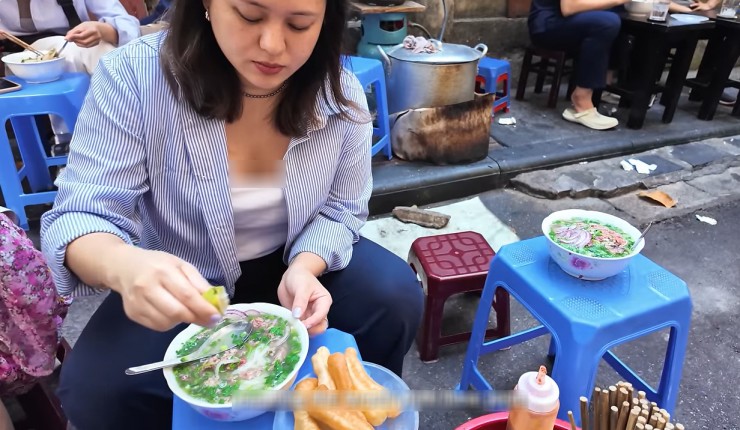 A bowl of pho with herbs at a Vietnamese street food stall